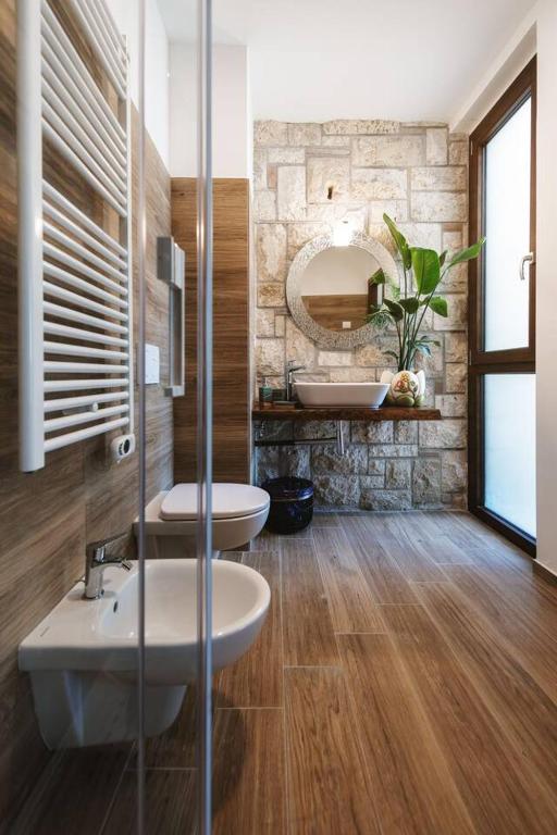 Bagno della camera con parete in pietra naturale e pavimento in legno